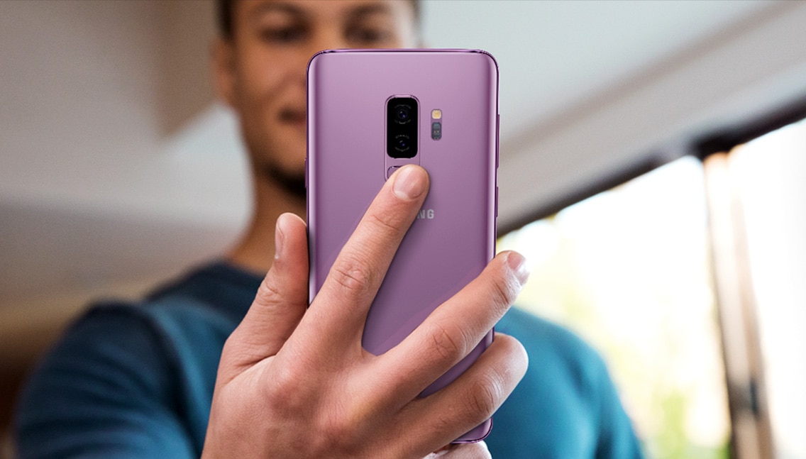 Photo d’une personne tenant un Galaxy S9+ pour montrer le positionnement du capteur d’empreinte digitale.