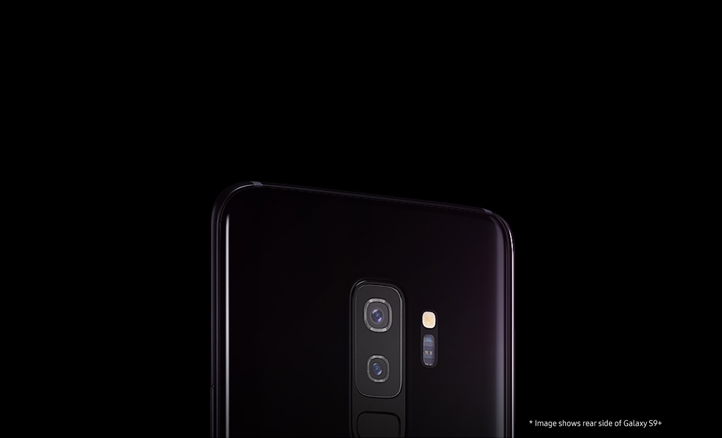 Soft lit against a dark backdrop, the rear side view of a Lilac Purple Galaxy S9+ emphasizes the dual camera and rear hardware, and sleek body design.