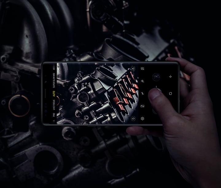 Slika osobe koja drži Galaxy Note9 i fotografira opremu pri slabom svjetlu, čime se prikazuju mogućnosti dvostrukog otvora blende