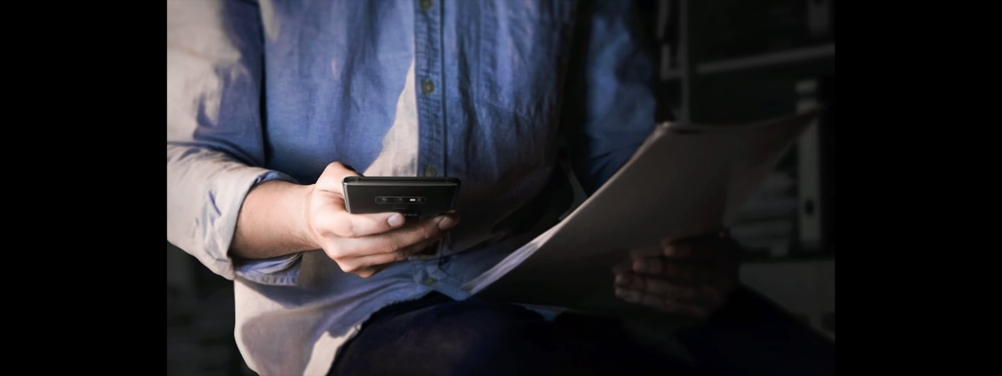 Vaizdas su žmogumi, laikančiu „Galaxy Note9“, prieblandoje naktį