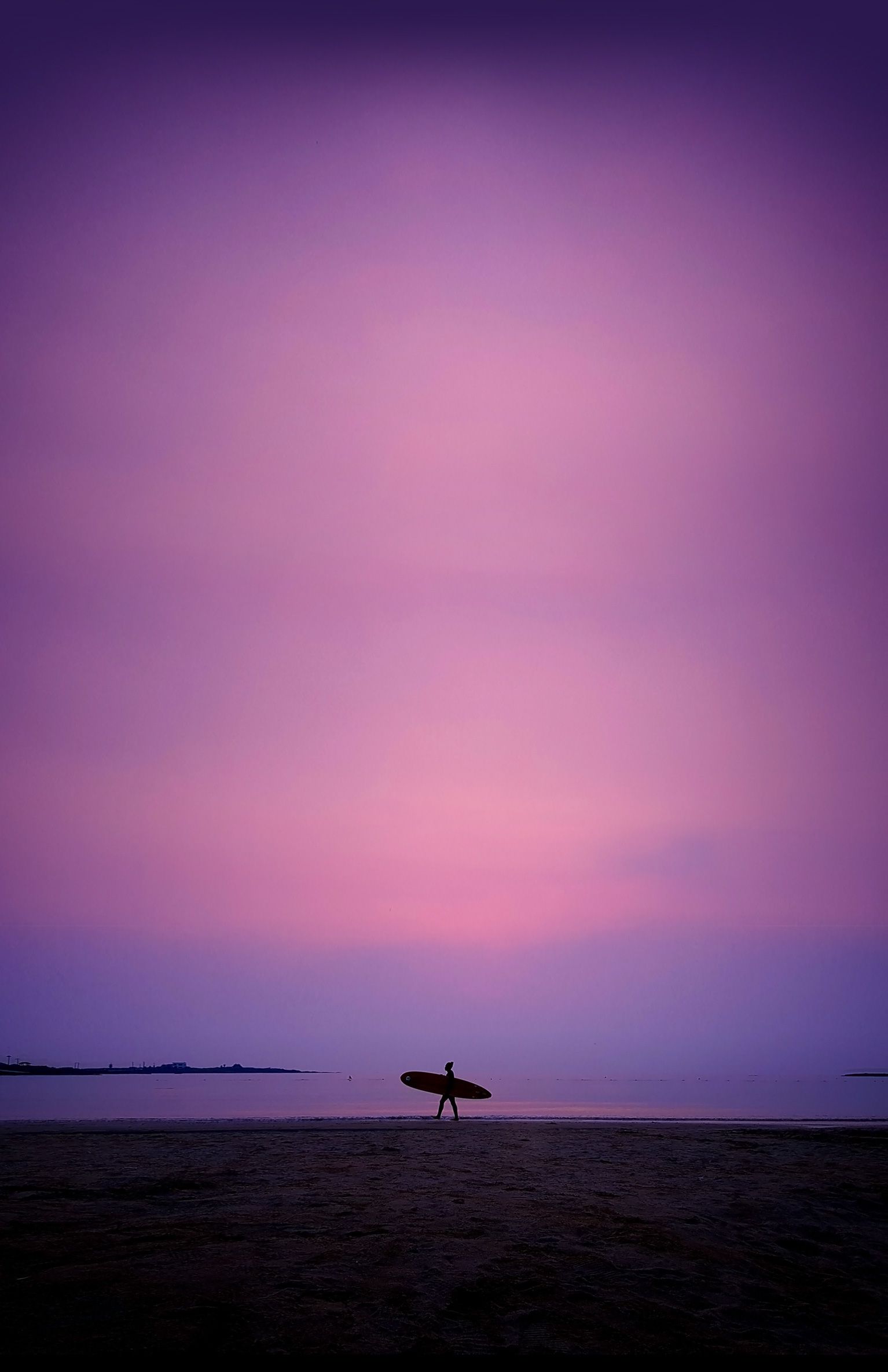 Full image of a woman holding a surfboard against a dusky purple sky