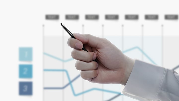 Simulerad bild av en person som håller S Pen med en presentation som visar ett linjediagram i bakgrunden. När personen klickar på S Pen-knappen byter presentationen bild och visar ett annat diagram.