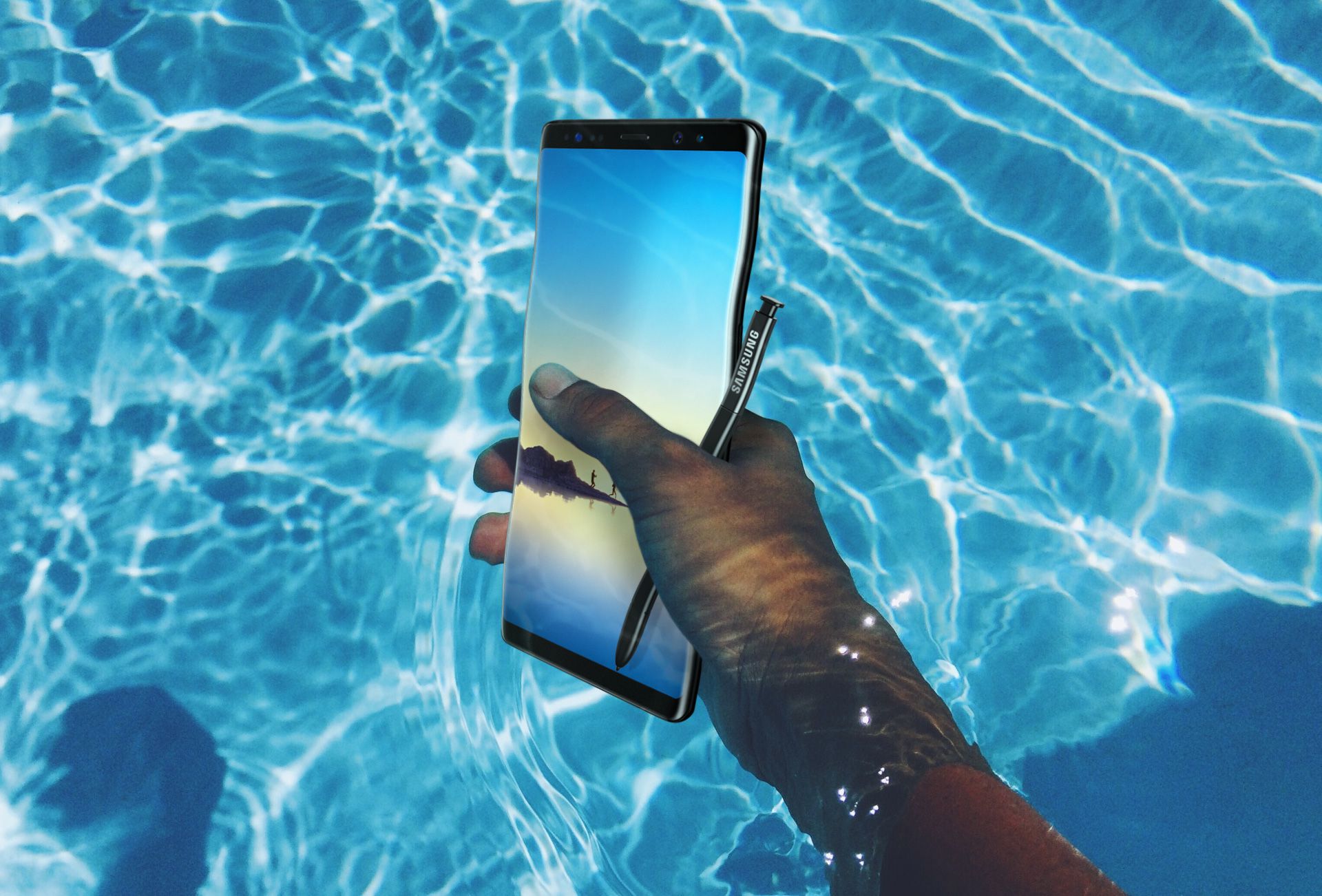 Image of hand holding the Galaxy Note8 and the S Pen underwater in a swimming pool
