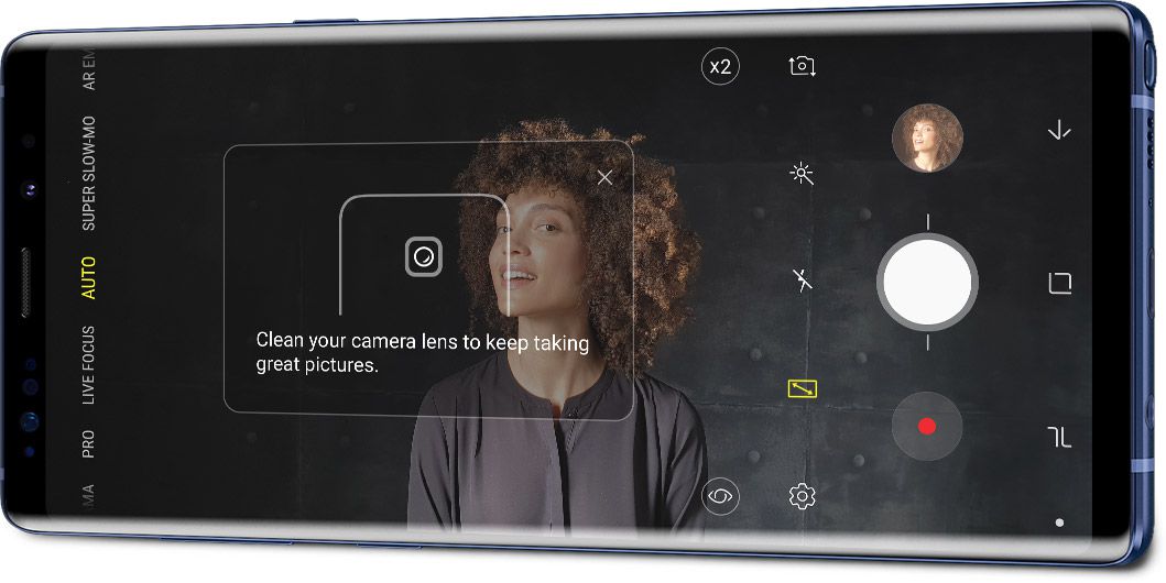 Το Galaxy Note9 σε οριζόντια λειτουργία όπως φαίνεται υπό γωνία με ένα πορτρέτο και τη διεπαφή ανίχνευσης ατελειών στην οθόνη, με την ειδοποίηση «Καθαρίστε τον φακό της κάμεράς σας για να συνεχίσετε να βγάζετε φωτογραφίες».