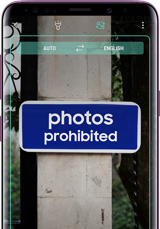 Galaxy S9+ displaying a translated sign with the untranslated sign in the background