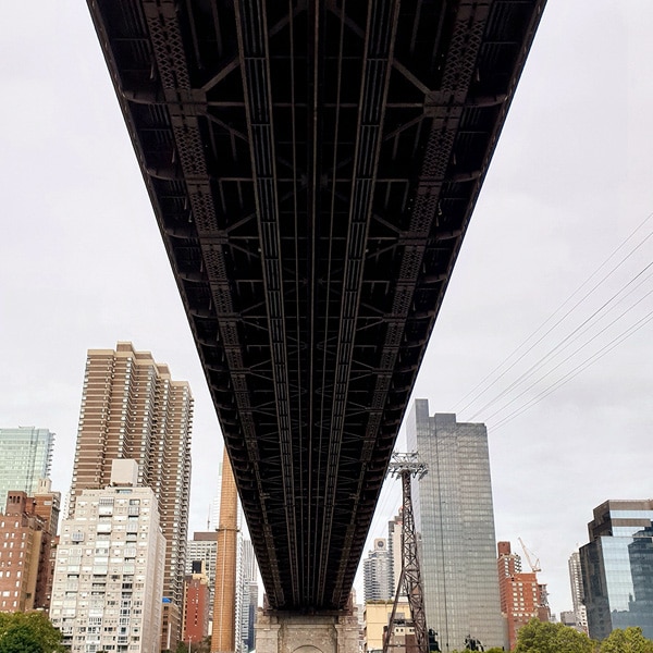 A photo taken by Galaxy Note9 of city buildings, with the dark underside of a bridge cutting through the center of the photo
