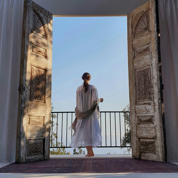 A photo taken by Galaxy Note9 of a woman in a white dress standing out on a balcony, framed by white doors