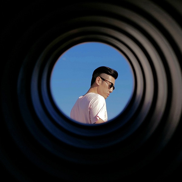 A photo taken by Galaxy Note9 of a man wearing sunglasses, seen through a round tube