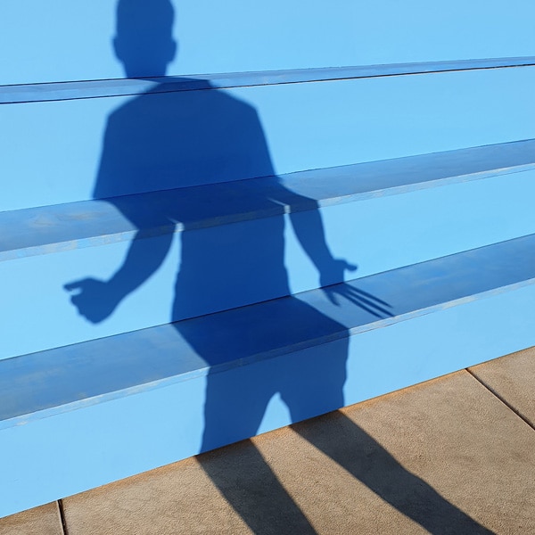 A photo taken by Galaxy Note9 of blue stairs with a human shadow cast on them